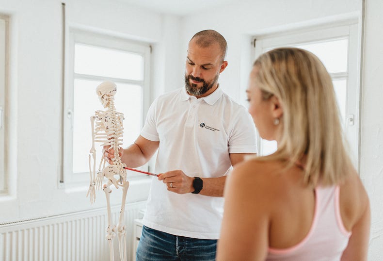 Fachkundiges Diagnosegespräch zur präzisen Schmerzanalyse. Mit einem anatomischen Model erläutere ich meiner Patientin die betroffene Bereiche und bespreche individuelle Behandlungsmöglichkeiten